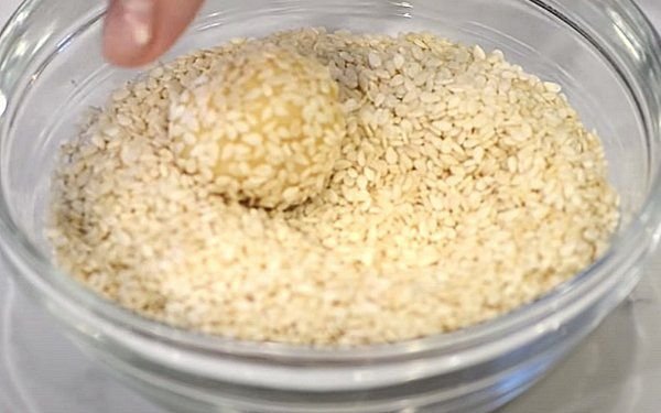 В мисочку насыпьте семена кунжута и обваляйте в них шарики песочного теста.